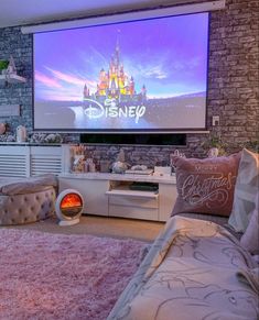 a living room with a large screen tv on the wall and pink rugs in front of it