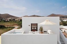 an outdoor jacuzzi is set up on the side of a building with mountains in the background