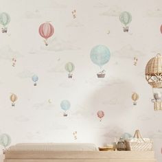 a baby's room with hot air balloons on the wall and a crib