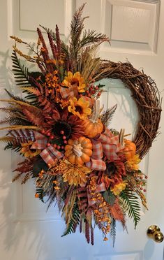 a wreath is hanging on the front door with fall foliage and flowers in oranges