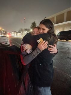 two women hugging each other on the street