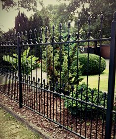 an iron fence in the middle of a park