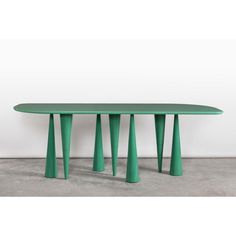 a green table sitting on top of a cement floor next to a white wall in a room