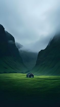 a house in the middle of a green field with mountains in the backgroud