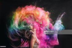 a woman with her hair blowing in the air and colored powder on her face as she looks up