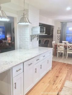 a kitchen with white cabinets and an island in front of a dining room table that has chairs around it