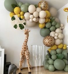 a giraffe standing in front of a bunch of balloons on the side of a wall