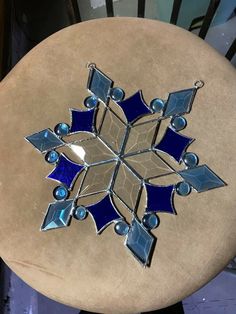 a blue and silver snowflake sitting on top of a wooden table next to a chair