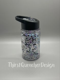 a jar filled with lots of glitter sitting on top of a white table next to a black lid