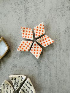 three pieces of ceramic sitting on top of a table next to each other, one with orange polka dots