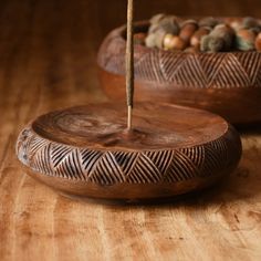 two wooden bowls sitting on top of a wooden table filled with rocks and wood sticks