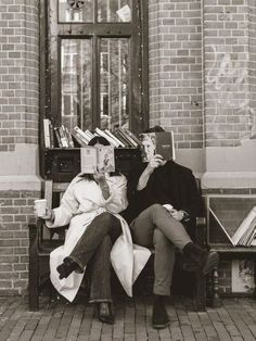 two people sitting on a bench reading books