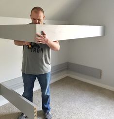 a man standing in front of a bed frame holding a piece of paper over his face