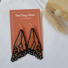 two pairs of beaded earrings sitting on top of a white table next to a card