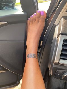 a woman's foot with a small tattoo on her left leg in a car