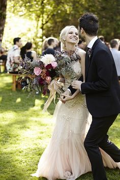 a bride and groom walking down the aisle at their outdoor wedding ceremony in an open field