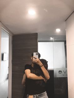 a woman taking a selfie in front of a bathroom mirror with her cell phone