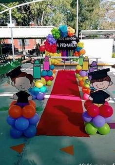 some balloons that are on the ground near a red carpet with people wearing hats and gowns