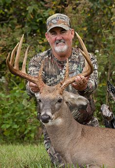 a man kneeling down next to a deer