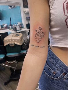 a woman with a tattoo on her arm that reads just one life and has flowers growing out of it