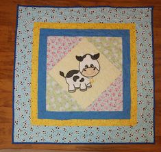 a small quilted cow on a wooden floor