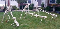 three skeleton sculptures in the grass near a house