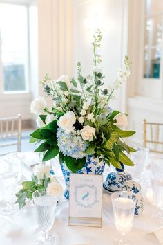 a blue and white vase filled with flowers sitting on top of a table next to plates