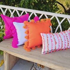 four different colored pillows on a bench