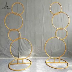 two gold metal circles on stands against a white backdrop