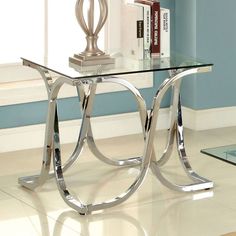 a glass and chrome table with books on it next to a window in a blue room