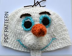 a crocheted white hat with blue eyes and nose is shown on top of a piece of paper