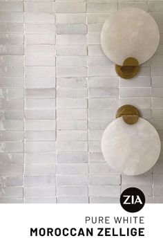 two round mirrors mounted on the side of a white tiled wall next to a toilet