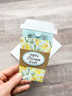 a hand holding up a card with the words happy nurses week written on it and an envelope