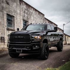 a black ram truck parked in front of a brick building on a cloudy day with no one around