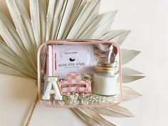 a pink and white box with some items in it next to a palm frond