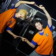 two young men standing next to each other in front of refrigerators with their hands up