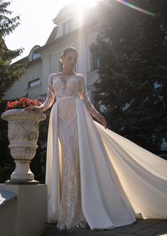 a woman in a wedding dress standing next to a planter with flowers on it