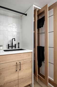 a kitchen with wooden cabinets and white tile backsplash, black faucets