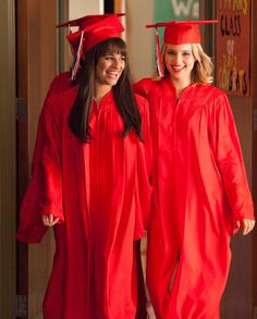 two women in red graduation gowns standing together