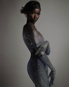 a woman in silver bodysuit posing with her hands on her hips and arms behind her back