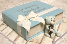 a teddy bear sitting on top of a book next to a small figurine