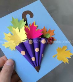 a hand is holding up some paper flowers with an umbrella on it and the number one