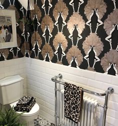 a white toilet sitting next to a black and white wallpaper with flowers on it