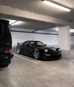 two cars parked in a parking garage next to each other on the floor and one is black