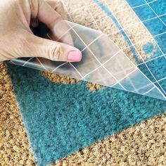 a person is using a piece of clear plastic to cut out the pattern on carpet