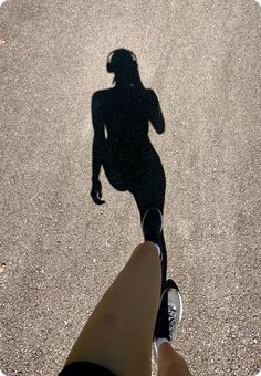 a person standing in the middle of a street with their shadow on the ground,