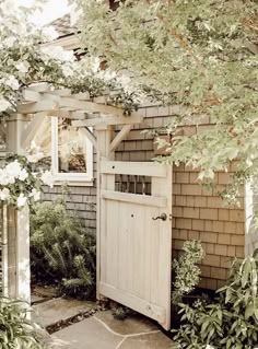 an open door to a small house with flowers growing on the front and side of it