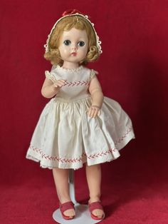 the doll is wearing a white dress with red trimmings on it's head