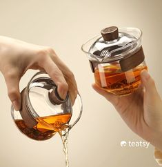 a person pouring tea into a glass cup