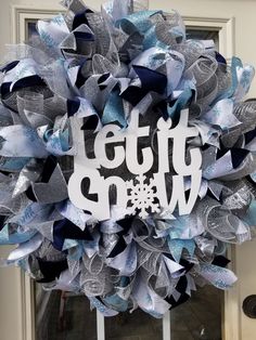 a wreath that says let it snow on the front door with blue and silver ribbons